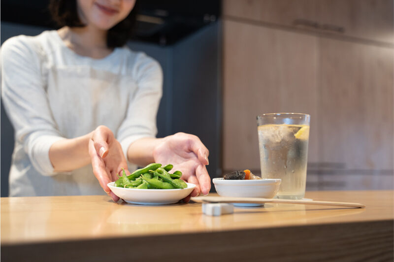 カウンターキッチンで料理を差し出す女性