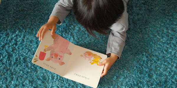 寝転がりながら絵本を読む幼児